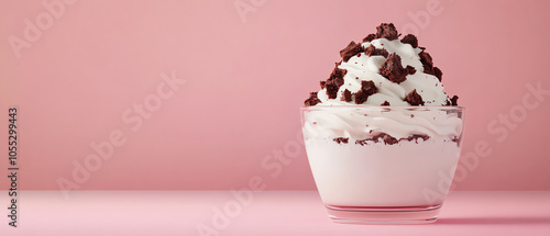 Delicious ice cream dessert topped with chocolate sprinkles in a glass bowl, set against a soft pink background, perfect for sweet treats.
