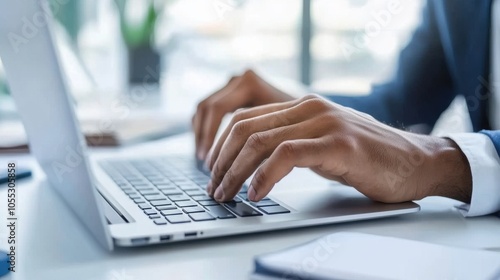 Hands typing on a laptop in a modern office setting.