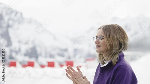 Frau reibt sich ihre kalten Hände im Skigebiet, bevor sie ins Restaurant geht