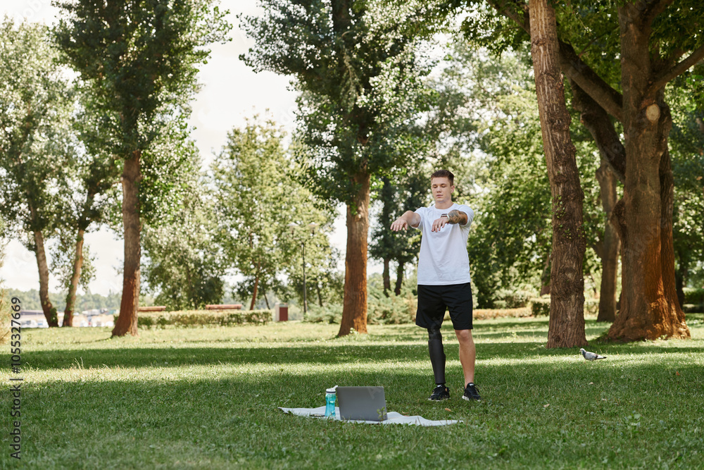 Tattooed young man with artificial leg working out in green park, engaging in an online fitness lesson Tattooed young man with artificial leg working out in green park, engaging in an online fitness lesson