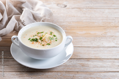 Cauliflower soup in bowl on wooden table. Copy space