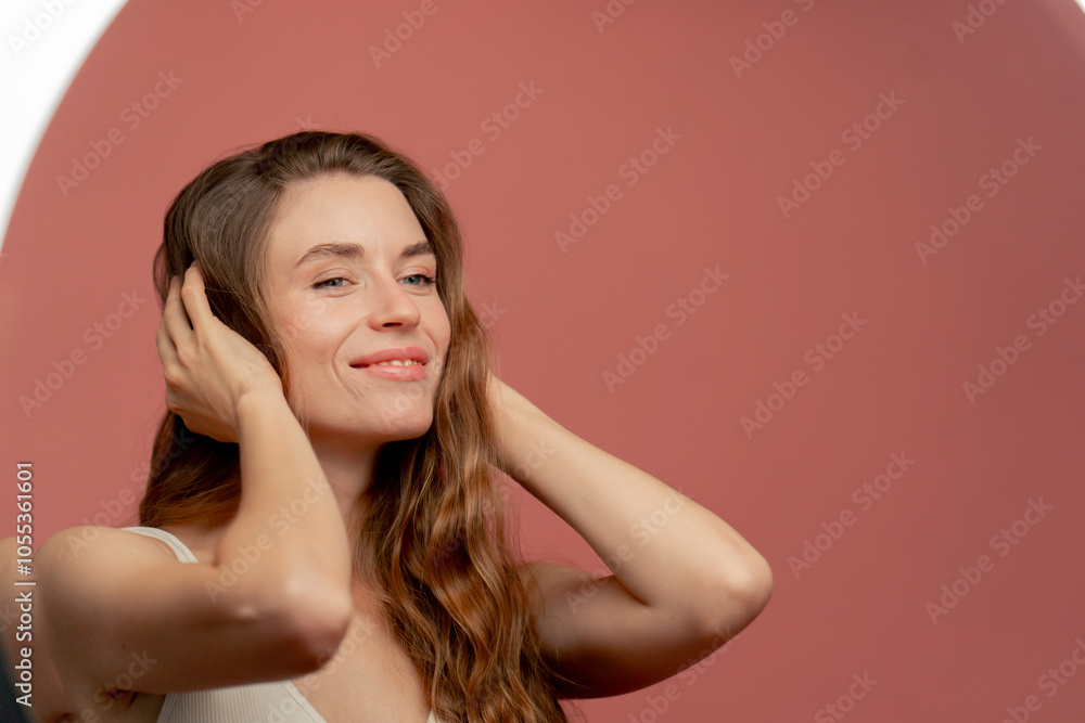 studio beauty shoot on pink background beautiful girl in white underwear admiring herself in the mirror smiling eyelashes beauty salon hands near her face studio beauty shoot on pink background beautiful girl in white underwear admiring herself in the mirror smiling eyelashes beauty salon hands near her face