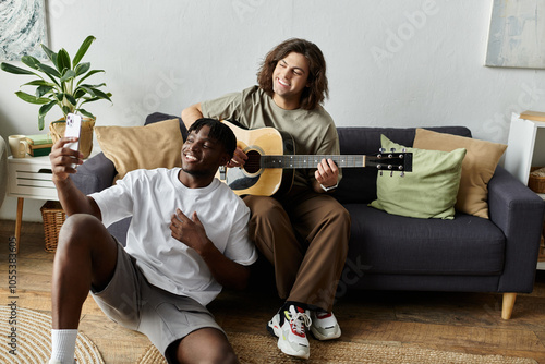 Two partners share a playful moment as one plays guitar while the other captures the fun on a phone.