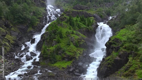 Cars driving over bridge in Norwegian highlands, Latefossen Waterfall, one of the most visited, Odda. Aerial Drone Shot photo