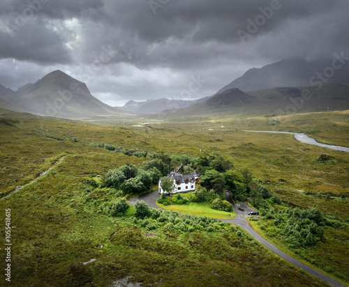 Aerial view of sligachan hotel surrounded by lush green landscape and winding road under cloudy skies, Isle of Skye, United Kingdom. photo