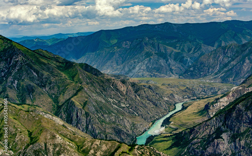 Aerial view of the majestic Katun River winding through a rugged mountain landscape with cliffs and a serene sky, Altai Republic, Russia.