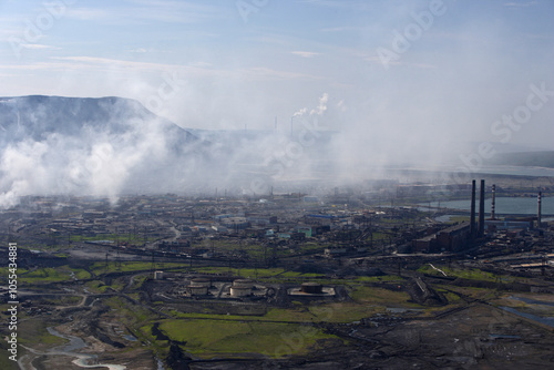 Aerial view of industrial factory with smokestacks amidst urban landscape and mountains, Norilskii, Russia. photo