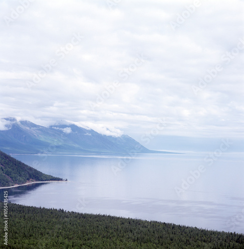 Aerial view of majestic mountains and tranquil sea surrounded by lush forest and clouds, eastern siberia, russia.