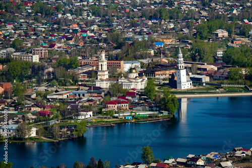 Aerial view of transfiguration cathedral with a picturesque river and quaint houses surrounded by greenery, Nevyansk, Russia.