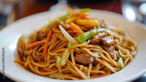 A plate of yaki soba, stir-fried noodles with vegetables, meat, and a savory sauce, garnished with pickled ginger.

