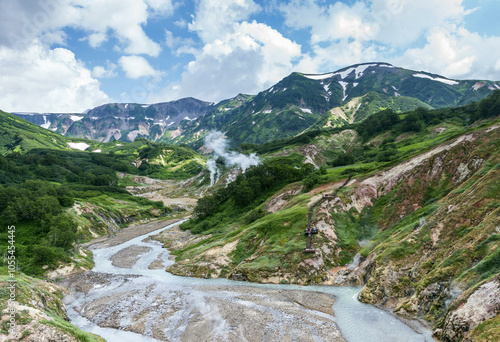 Aerial view of the breathtaking Valley of Geysers with majestic mountains and a serene river, Kamchatka Peninsula, Russia.