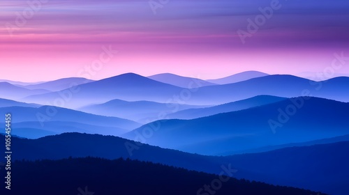 A misty mountain range at dusk with deep blue and purple hues in the sky