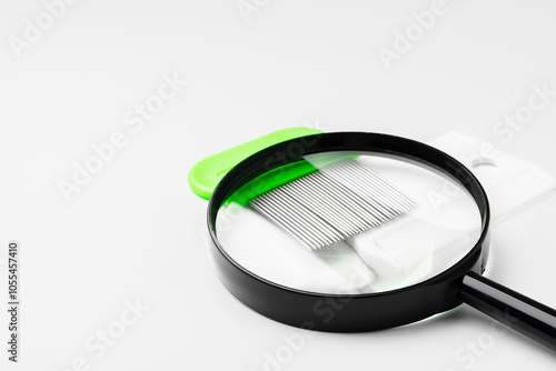 A magnifying glass and lice comb placed side by side on a clean white background