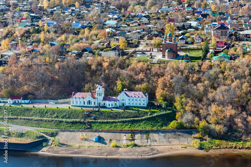 Aerial view of a picturesque village with colorful rooftops and a serene church by the kama river, Urzhum, Udmurt, Russia.