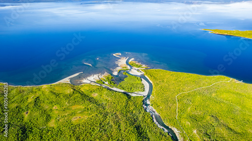 Aerial view of the serene delta of Abiskojakka River meeting the expansive Tornetrask Lake surrounded by lush forests, Abisko National Park, Sweden.