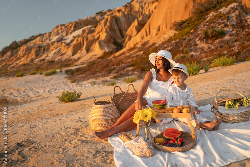 Fototapeta premium A serene moment of a mother and son having a picnic on the beach, surrounded by nature's beauty and sunlight.