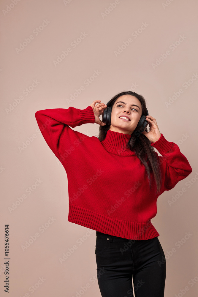 Happy woman wearing red sweater and headphones enjoying listening music on pink background. Happy woman wearing red sweater and headphones enjoying listening music on pink background.