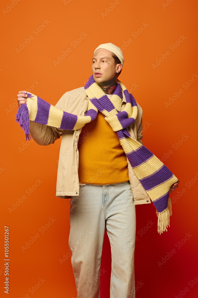 A young man adorned with tattoos styles a colorful scarf while showcasing his unique fashion. A young man adorned with tattoos styles a colorful scarf while showcasing his unique fashion.