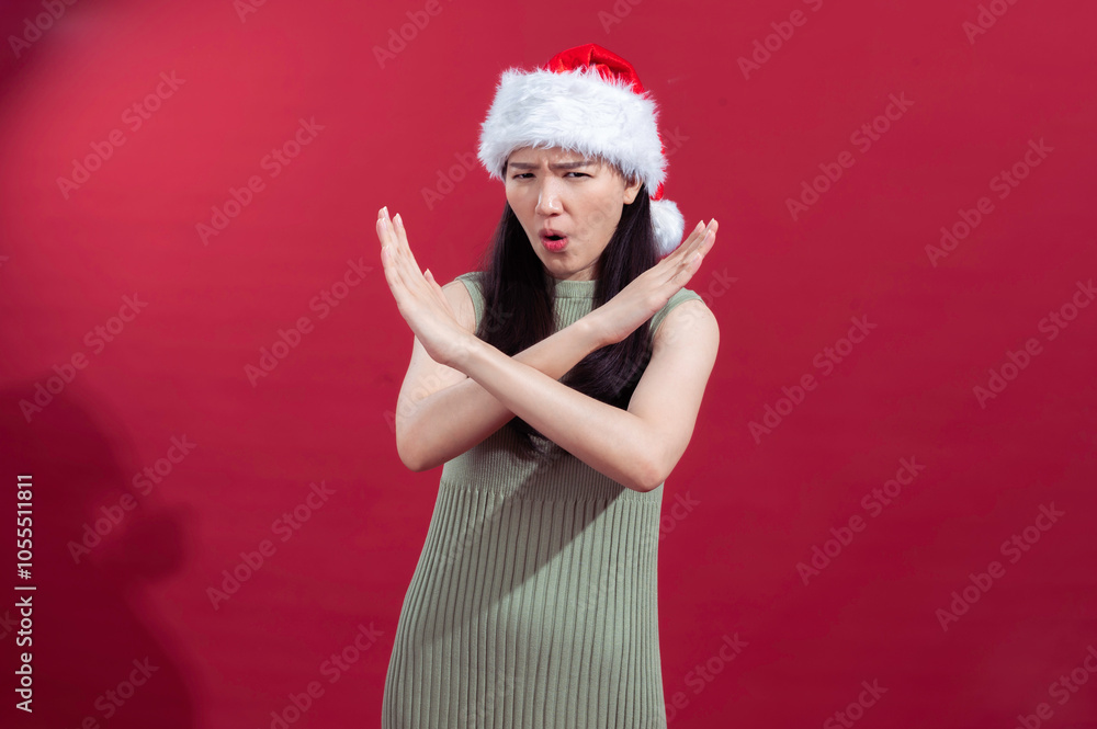 Asian woman wearing a green dress and a Santa hat poses with her arms crossed in an Asian woman wearing a green dress and a Santa hat poses with her arms crossed in an