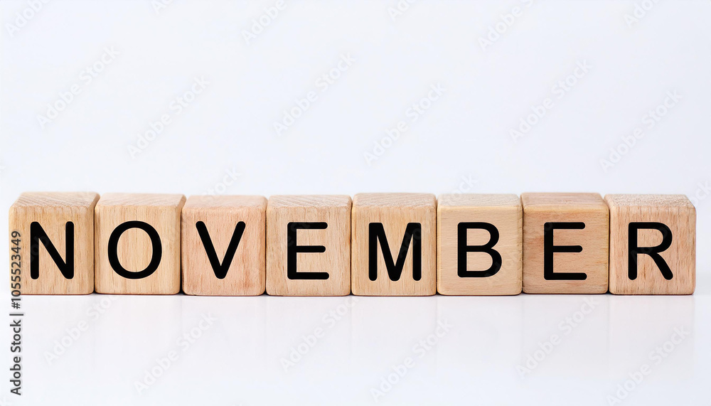 Fototapeta premium Wooden cubes with text NOVEMBER on white backdrop. Autumn season. Month of year. Wood block