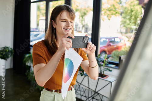 A non binary person enthusiastically takes photos of design concepts in a bright workspace. photo