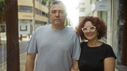 Middle-aged couple standing together on a city street during daytime, smiling, and enjoying an outdoor urban setting