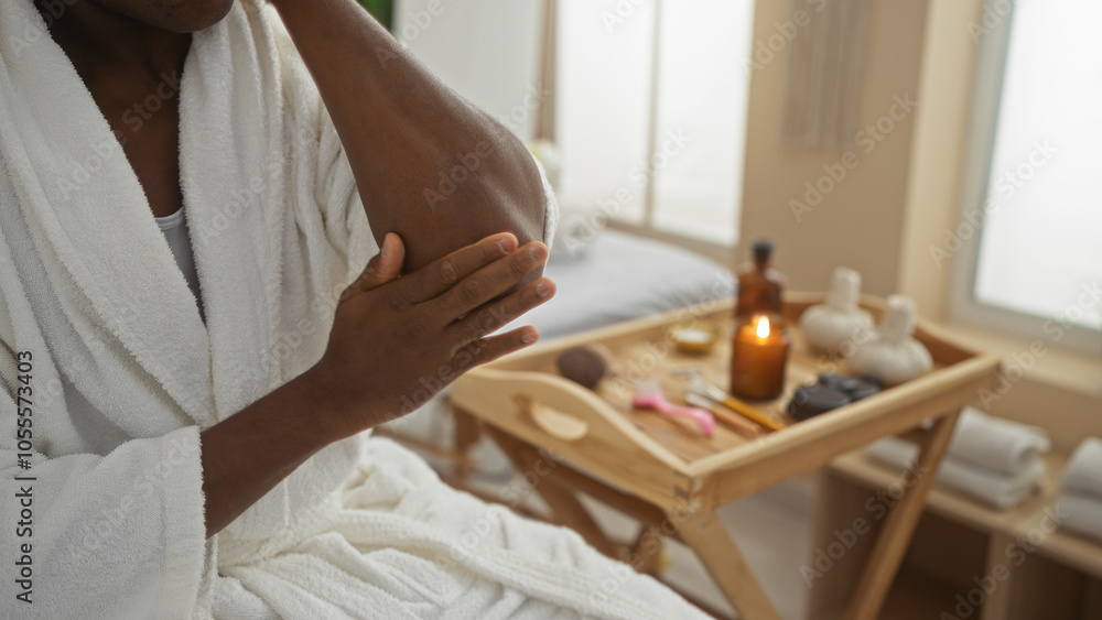 Young man in spa applying lotion on elbow in a serene wellness center with candles and beauty products Young man in spa applying lotion on elbow in a serene wellness center with candles and beauty products