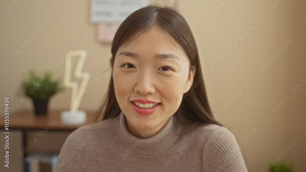 A smiling young asian woman in a cozy interior with a modern lamp and plant A smiling young asian woman in a cozy interior with a modern lamp and plant