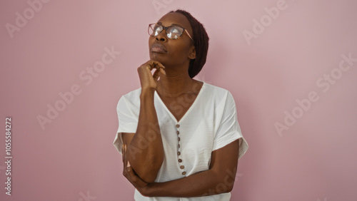 African american woman wearing glasses in a thoughtful pose, over an isolated pink background wall, looking stylish and contemplative in her white blouse. photo