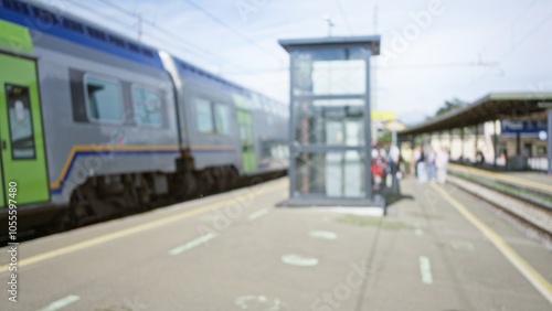 Wallpaper Mural Blurred scene showing people waiting at a busy train station platform with a moving train in the background under bright daylight. Torontodigital.ca