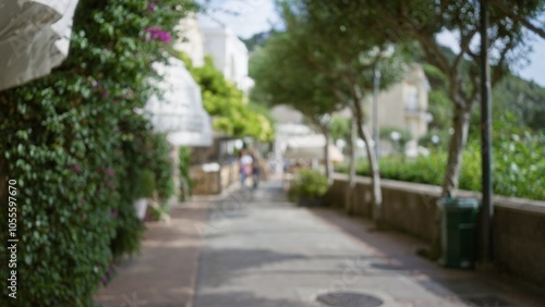 Blurred view of a picturesque street on capri island with lush greenery and distant figures under clear skies, capturing the essence of luxury and tranquility.