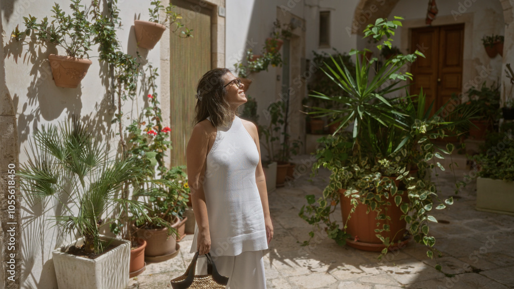 Young hispanic woman enjoying a sunny day in the charming old streets of locorotondo, puglia, italy, surrounded by lush plants and white historic buildings in the town center. Young hispanic woman enjoying a sunny day in the charming old streets of locorotondo, puglia, italy, surrounded by lush plants and white historic buildings in the town center.