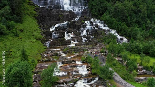 Aerial view of tvinde waterfall cascading through lush green forest and rocky landscape, skulestadmo, norway. photo