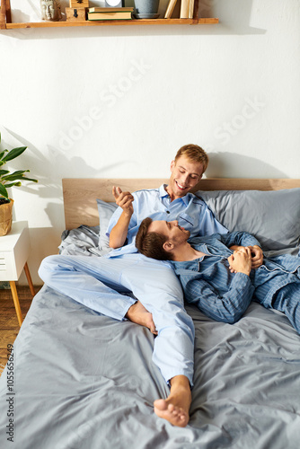 A loving gay couple shares playful conversation while relaxing together in their pajamas on a lazy morning.