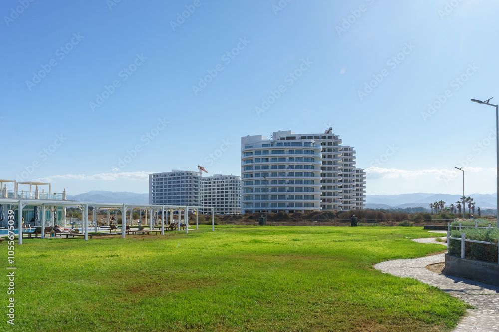 Serene green landscape with modern buildings and clear skies near the coastal shore. Serene green landscape with modern buildings and clear skies near the coastal shore.