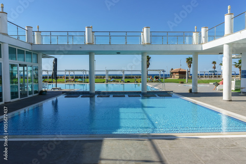 A serene swimming pool with ocean views at a luxurious beachfront resort under a clear blue sky.