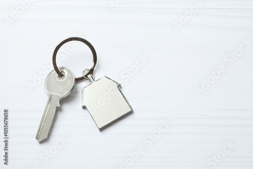 Metallic key with keychain in shape of house on white background