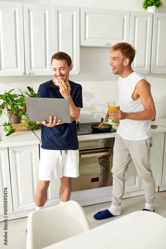 Fototapeta premium A happy couple making lunch and using laptop in their contemporary kitchen.