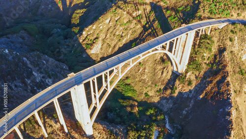 A stunning view of the iconic Bixby Creek Bridge on California Highway 1. The bridge stretches over picturesque cliffs and turquoise Pacific waters, creating a unique landscape and travel atmosphere.