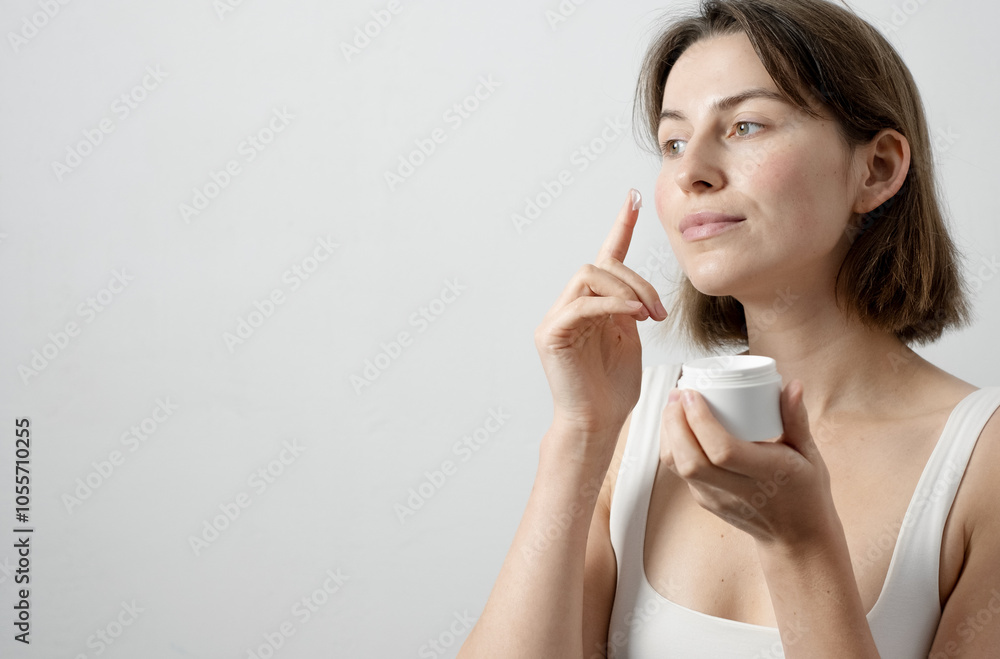 Woman moisturizing face with cream in morning Woman moisturizing face with cream in morning