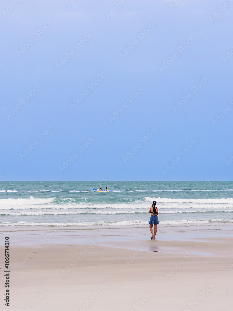 Back view of happy carefree woman using mobile phone at beach. Woman using smartphone standing at beach. Beautiful lovely young woman spending time at beach. Concept of travel, tourism and vacation. Back view of happy carefree woman using mobile phone at beach. Woman using smartphone standing at beach. Beautiful lovely young woman spending time at beach. Concept of travel, tourism and vacation.