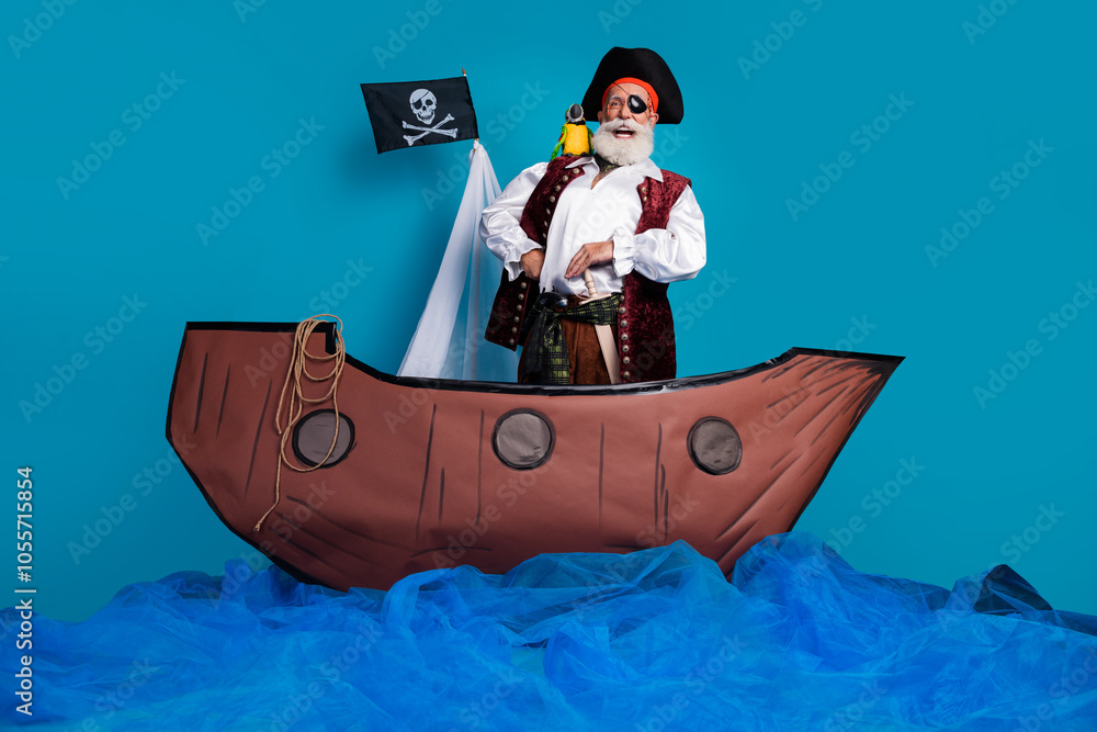 Naklejka premium Photo of positive funny man pirate medieval history hero swim boat isolated on blue color background