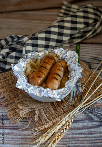 Grilled sausages with sauerkraut wrapped in aluminum foil on rustic wooden table