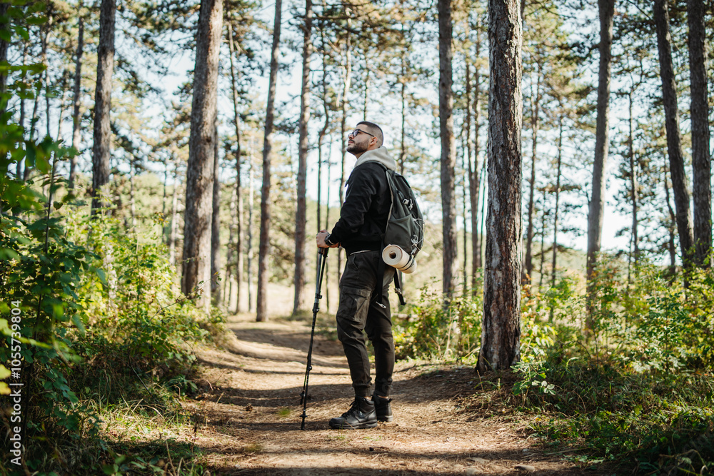 Young caucasian man hiking or trekking through the forest Young caucasian man hiking or trekking through the forest