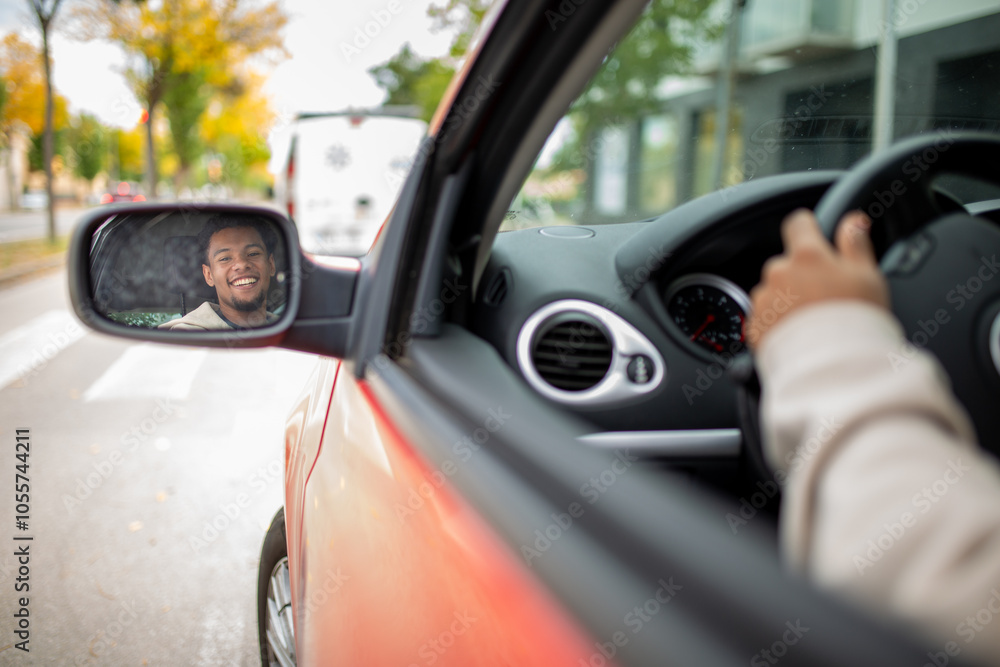 Man smiling in car rear-view mirror while driving in city Man smiling in car rear-view mirror while driving in city