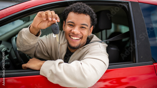 Smiling young man holding car key in red car window