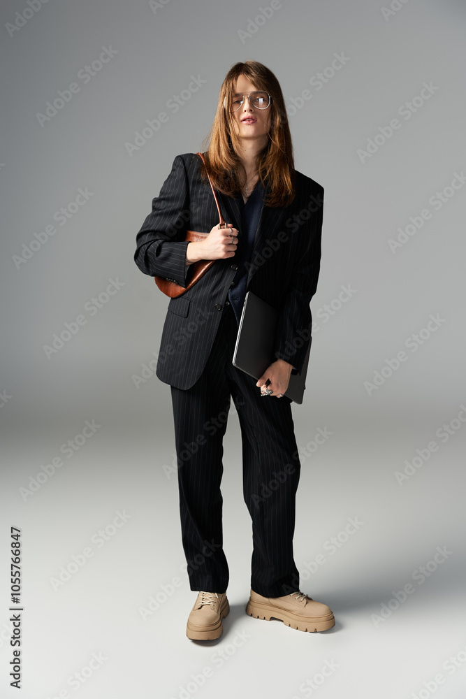 A fashionable young man stands confidently with a laptop and bag, showcasing style. A fashionable young man stands confidently with a laptop and bag, showcasing style.