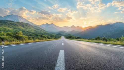 A long, straight road leading towards a mountain range at sunset.