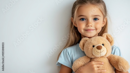 In a professional studio, a young girl with blonde hair and blue eyes beams with joy as she hugs her teddy bear close, creating an adorable and heartwarming moment photo