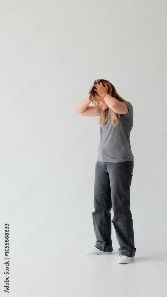Stressed Caucasian young adult woman in grief and shock, standing on white background. Fright, distraught, panic concept. Vertical video. Stressed Caucasian young adult woman in grief and shock, standing on white background. Fright, distraught, panic concept. Vertical video.